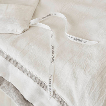 Premium white bedding with textured layers, soft linen material, and a Harbor House ribbon.